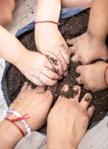 Hands of various ages digging in soil, symbolizing growth and teamwork.