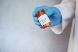 Healthcare worker holding a COVID-19 antiviral treatment in a prescription bottle.